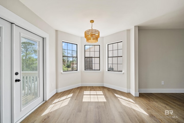 26498 Carondelette Dr, Orange Beach, AL 36561 - unfurnished dining area with wood finished floors, a chandelier, and baseboards