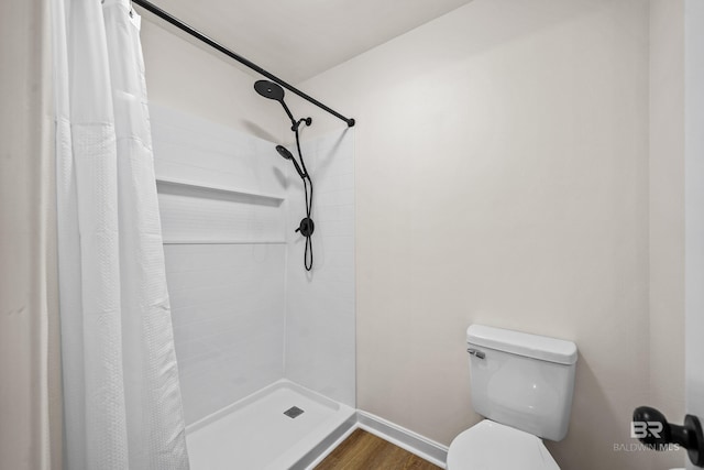 26498 Carondelette Dr, Orange Beach, AL 36561 - full bathroom featuring toilet, a tile shower, wood finished floors, and baseboards