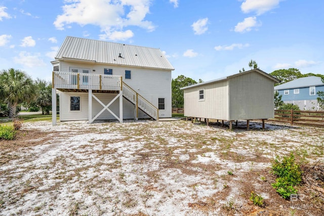 26498 Carondelette Dr, Orange Beach, AL 36561 - back of property with stairs, a deck, fence, metal roof, and an outdoor structure