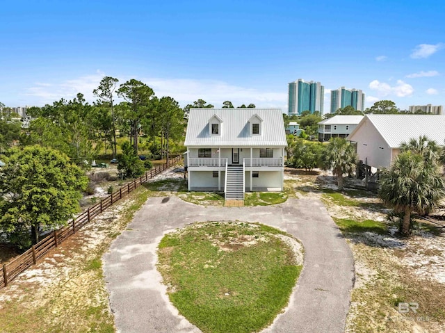 26498 Carondelette Dr, Orange Beach, AL 36561 - coastal inspired home featuring stairs, curved driveway, metal roof, covered porch, and fence