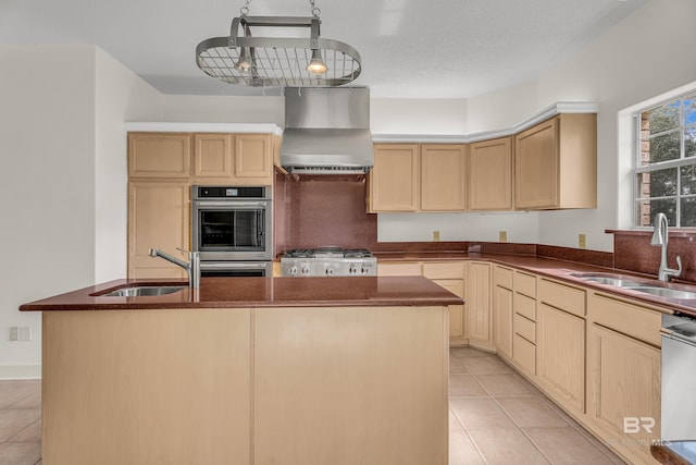 kitchen featuring light brown cabinetry, appliances with stainless steel finishes, a sink, and wall chimney exhaust hood