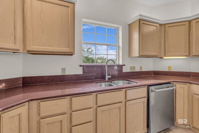 kitchen featuring light brown cabinetry, dark countertops, a sink, and dishwasher