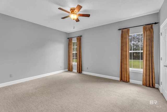 empty room featuring a healthy amount of sunlight, carpet floors, and a ceiling fan