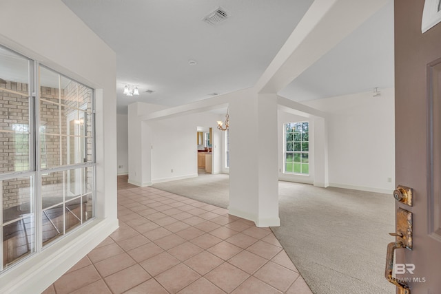 spare room with visible vents, baseboards, light colored carpet, light tile patterned floors, and a notable chandelier