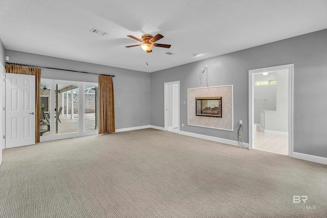 unfurnished living room featuring visible vents, baseboards, a tile fireplace, a ceiling fan, and carpet