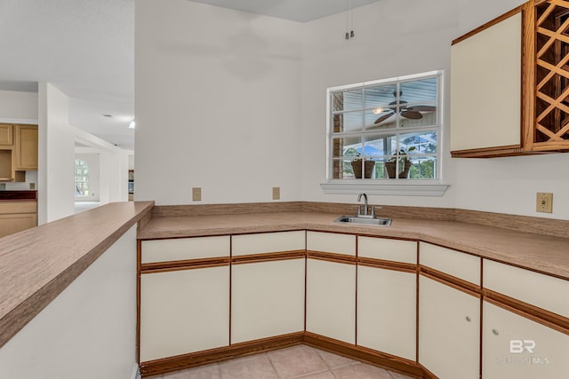 kitchen with light tile patterned floors, ceiling fan, a wealth of natural light, and a sink
