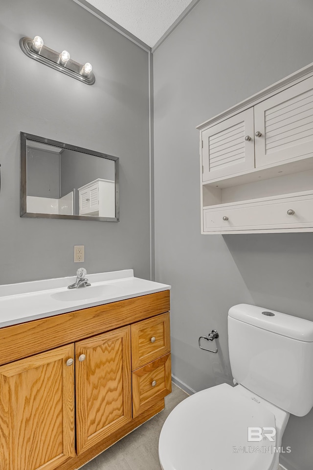 half bathroom featuring toilet, baseboards, and vanity