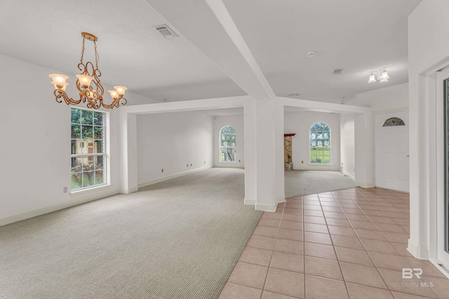 interior space featuring visible vents, light tile patterned floors, baseboards, an inviting chandelier, and light carpet