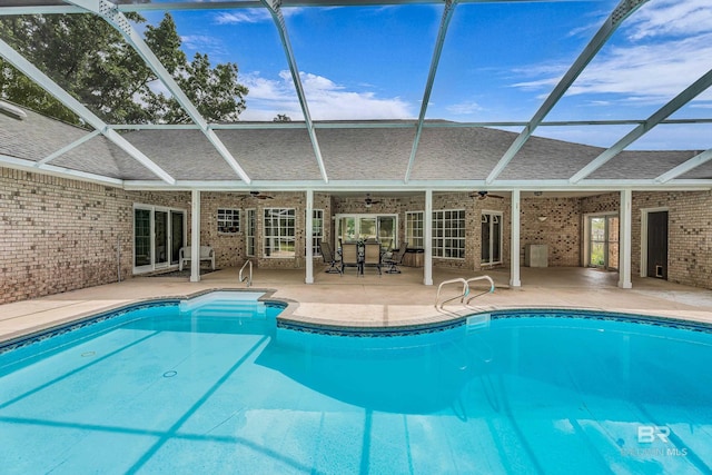 outdoor pool with glass enclosure, ceiling fan, and a patio area
