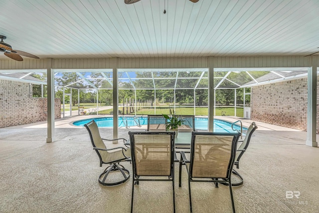 view of patio with glass enclosure, a ceiling fan, and an outdoor pool