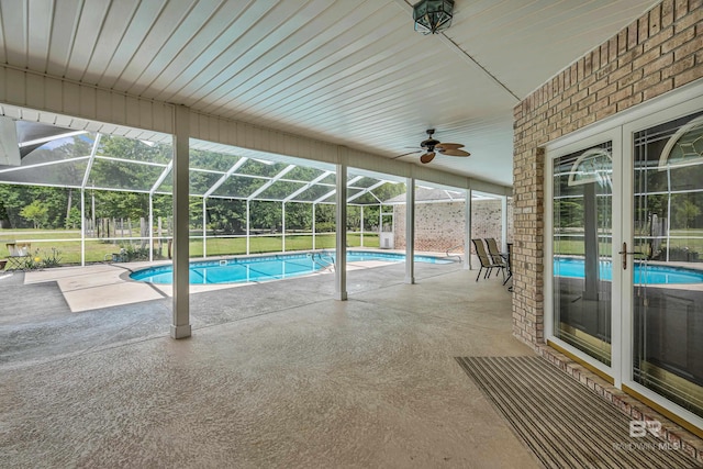 outdoor pool with a patio, ceiling fan, and glass enclosure