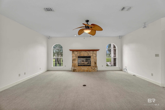 unfurnished living room featuring carpet flooring, a ceiling fan, visible vents, and a healthy amount of sunlight