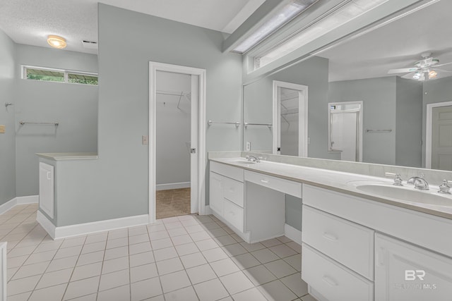 bathroom with double vanity, a ceiling fan, tile patterned floors, a spacious closet, and a sink