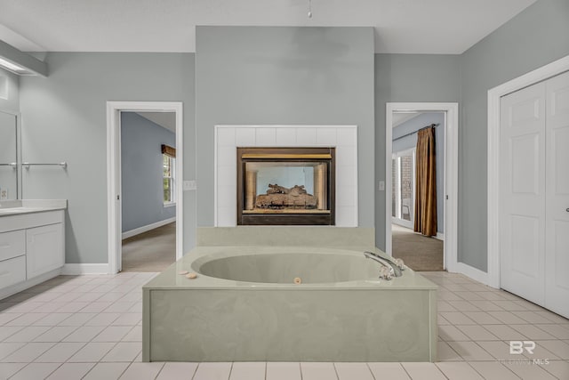 full bath featuring a whirlpool tub, vanity, a fireplace, and tile patterned floors