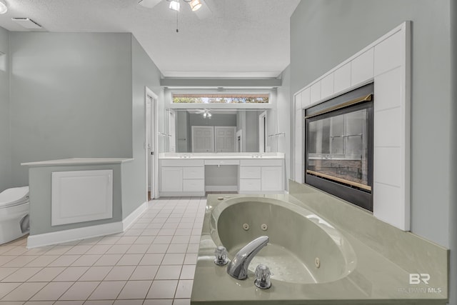 bathroom with ceiling fan, tile patterned flooring, vanity, a textured ceiling, and a jetted tub
