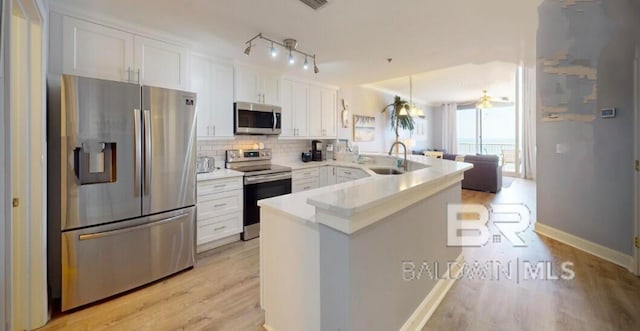 kitchen featuring kitchen peninsula, appliances with stainless steel finishes, light wood-type flooring, and white cabinetry