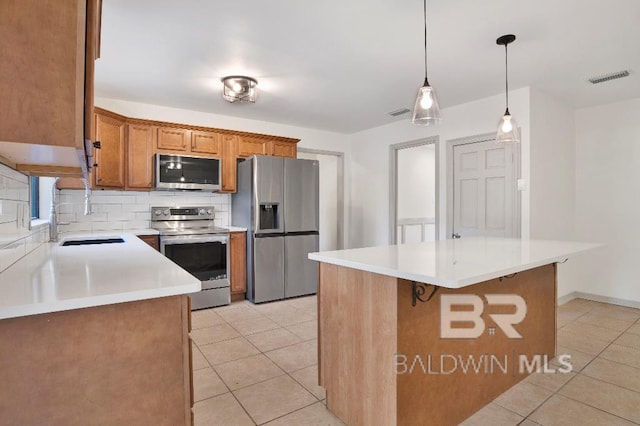 kitchen featuring light tile patterned floors, decorative backsplash, appliances with stainless steel finishes, brown cabinets, and a sink