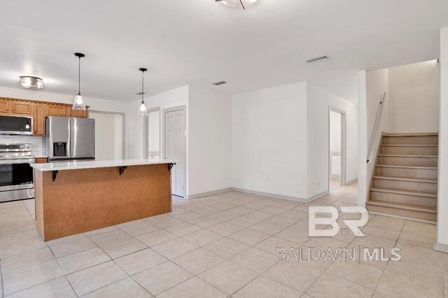 kitchen featuring visible vents, brown cabinetry, stainless steel appliances, light countertops, and backsplash