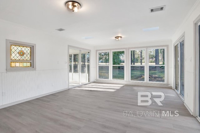 unfurnished room with a wainscoted wall, plenty of natural light, and visible vents