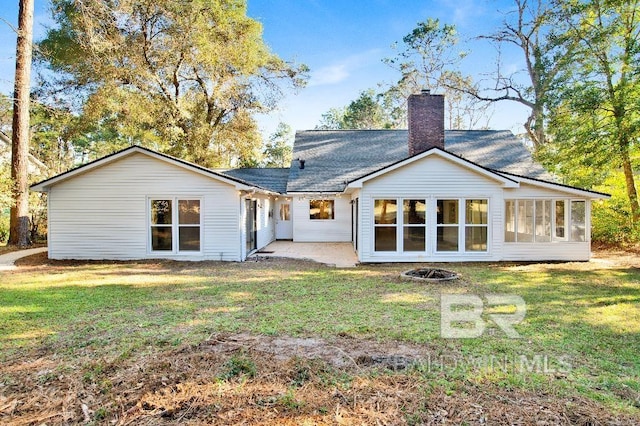 back of property with a fire pit, a yard, a chimney, and a patio