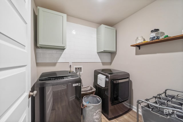 laundry room featuring cabinets, light wood-type flooring, and washing machine and clothes dryer