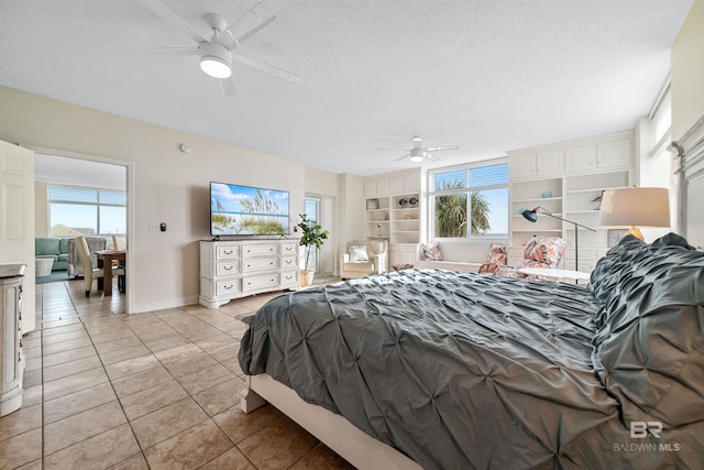 bedroom featuring light tile patterned floors, ceiling fan, a textured ceiling, and baseboards