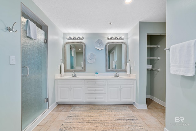 full bath featuring a textured ceiling, tile patterned floors, a shower stall, and a sink