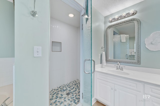 full bath with a textured ceiling, a tub to relax in, a stall shower, and vanity