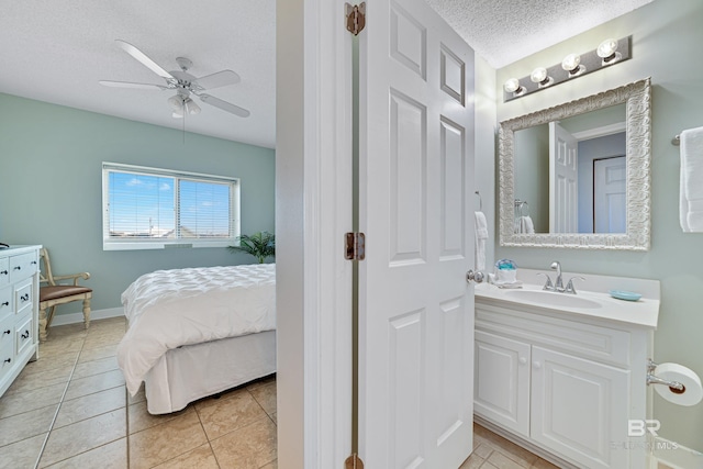 interior space with ensuite bathroom, a textured ceiling, tile patterned flooring, ceiling fan, and vanity