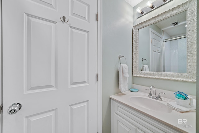 bathroom with a shower with door, visible vents, and vanity