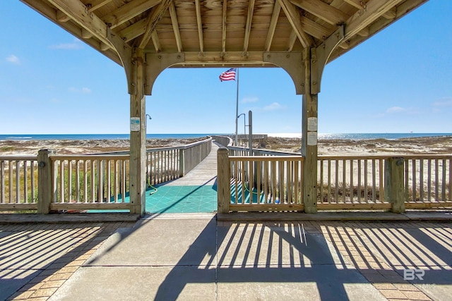 deck featuring a gazebo, a beach view, and a water view