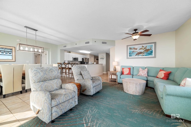 living room featuring light tile patterned flooring, ceiling fan with notable chandelier, and visible vents