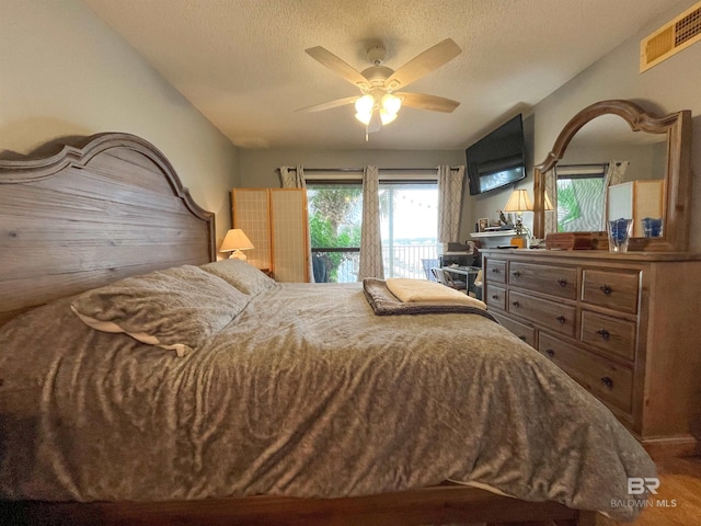 bedroom featuring ceiling fan, a textured ceiling, and access to exterior