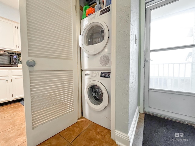 washroom featuring stacked washer and clothes dryer and light tile patterned flooring