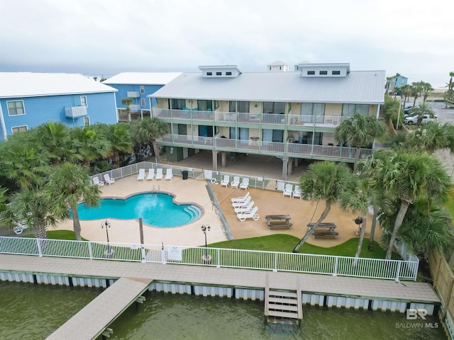 view of pool with a dock, a water view, and a patio area