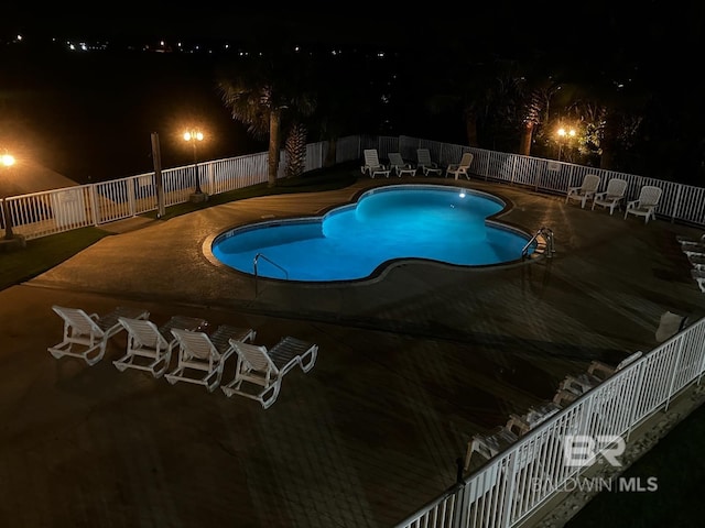 pool at night featuring a patio