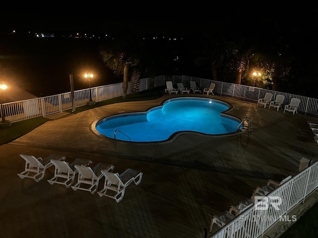 pool at twilight featuring a patio area