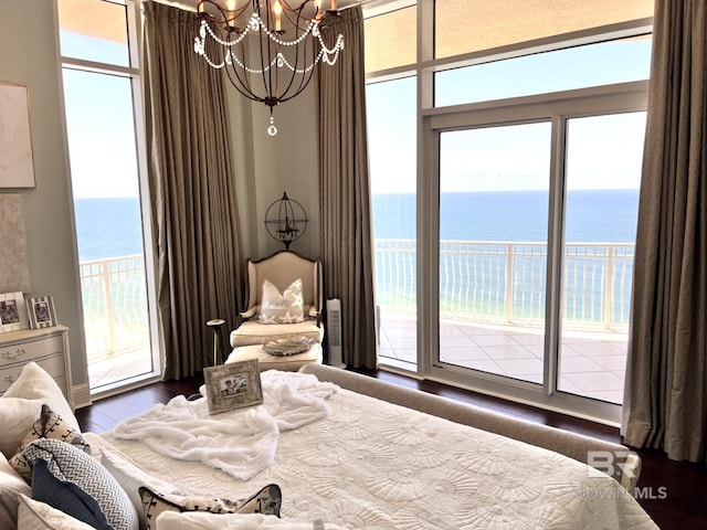 bedroom with multiple windows, access to outside, a notable chandelier, and a water view