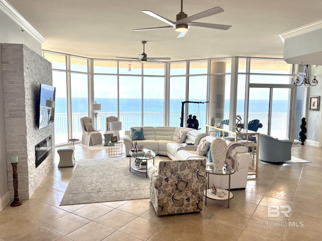 living room with a water view, ceiling fan, expansive windows, a stone fireplace, and a healthy amount of sunlight