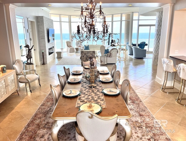 dining space with a water view, a notable chandelier, and light tile patterned floors