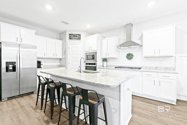 kitchen with stainless steel appliances, white cabinetry, and wall chimney range hood