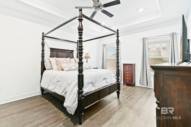 bedroom with hardwood / wood-style flooring, ceiling fan, ornamental molding, and a raised ceiling