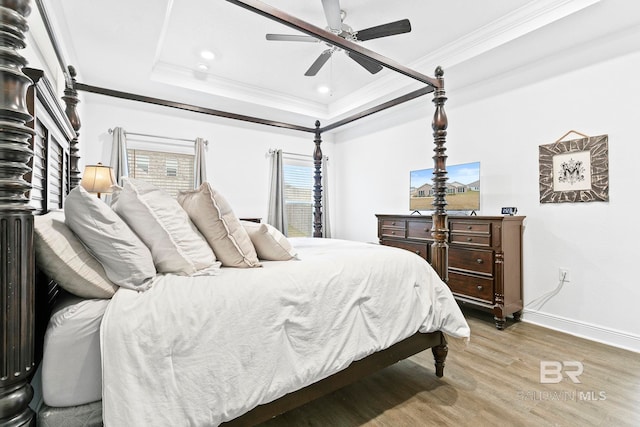 bedroom with ceiling fan, ornamental molding, a tray ceiling, and wood-type flooring