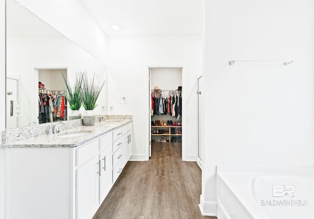 bathroom featuring hardwood / wood-style flooring, vanity, and a tub to relax in