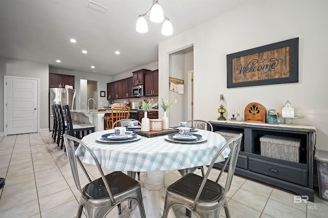 dining area with sink, a chandelier, and light tile patterned floors