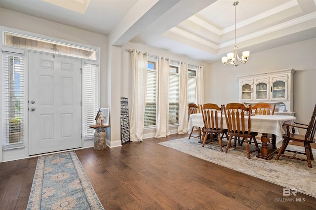 dining area with a healthy amount of sunlight, an inviting chandelier, dark wood-type flooring, and a raised ceiling