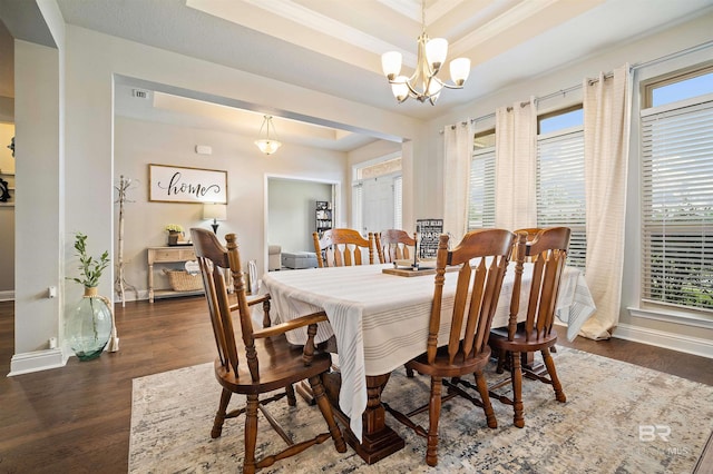 dining area featuring an inviting chandelier, a wealth of natural light, a tray ceiling, and dark hardwood / wood-style floors