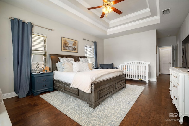 bedroom featuring a raised ceiling, crown molding, dark hardwood / wood-style flooring, and ceiling fan