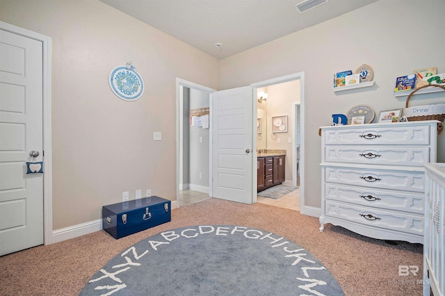 bedroom with ensuite bath and light carpet