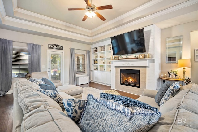 living room with ceiling fan, a raised ceiling, and dark hardwood / wood-style flooring